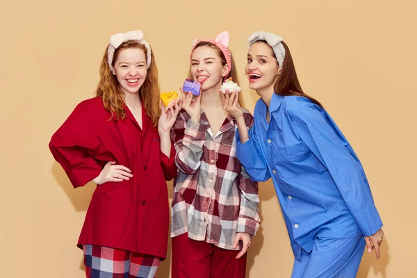 Feliz Sonriente Chicas Jóvenes Pijamas Colores Comiendo Dulces Divirtiéndose Contra —  Fotos de Stock