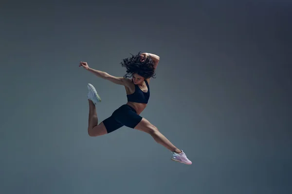 行动中 运动的艺术 迷人的年轻女子 身材纤细 适合在灰色工作室背景下进行身体训练 跳啊运动生活方式 身体护理 健康的概念 — 图库照片