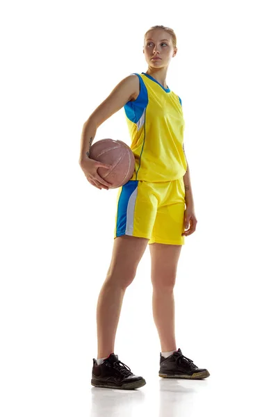全长形象的年轻女孩 身穿黄色制服的女篮球运动员与球在白色工作室的背景 职业运动 业余爱好 健康生活方式 动作和运动的概念 — 图库照片