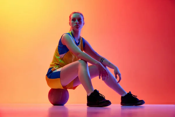 試合後 若い女の子 制服を着た女性バスケットボール選手 ポーズをとって 白いスタジオの背景にボールに座っている プロスポーツ 健康的なライフスタイル アクションと運動の概念 — ストック写真