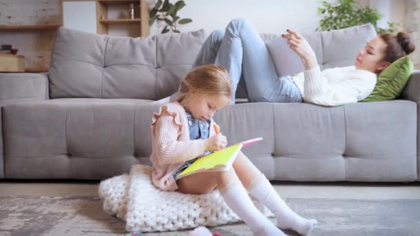 Young Woman Mother Lying Couch Reading Little Daughter Sitting Floor — Stock Video