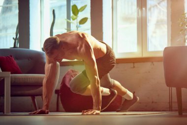 Kaslı, rahatlamış, gündüz vakti evde üstsüz ve güçlü vücut eğitimi almış dağ tırmanışı egzersizleri yapan genç bir adam. Spor yaşam tarzı, vücut ve sağlık, spor ve sağlık anlayışı