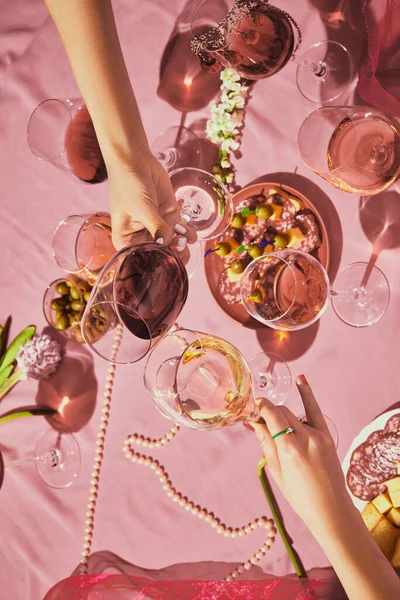 ピンク色の質感の背景にローズワインで満たされたガラスをクリンクする女性の手の垂直画像 前菜とテーブルクロス 味の概念は ワインの劣化 お祝い ワイン造り — ストック写真