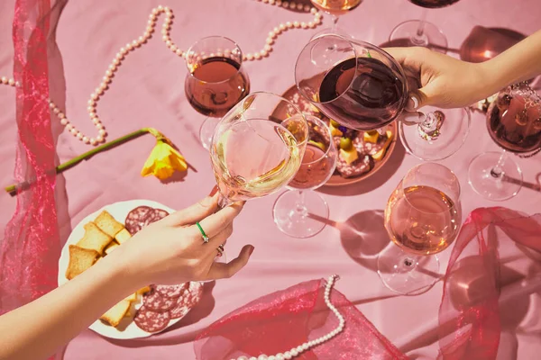 ピンクの質感の背景にローズワインで満たされたガラスをクリックする女性の手 前菜とテーブルクロス アルコール ワインの劣化 お祝い ワイン造りの概念 — ストック写真