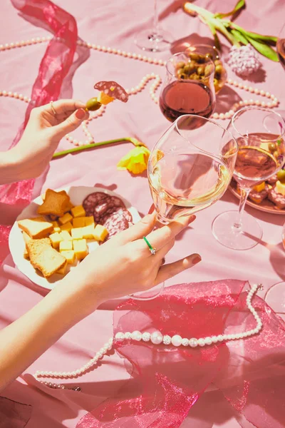 ピンク色の質感の背景にローズワインで満たされたガラスを保持する女性の手の垂直画像 前菜とテーブルクロス アルコール ワインの劣化 お祝い ワイン造りの概念 — ストック写真