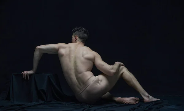 黒のスタジオを背景に下着姿でポーズをとる筋ジストロフィー男のバックビューポートレート 骨董品の彫刻のように 男性の体の美学 男性の美しさ インスピレーション 芸術の概念 — ストック写真