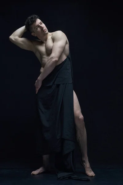 全长的英俊男子肖像画 身材矮小 肌肉松驰 赤身裸体 穿着深色面料 背景是黑色的工作室 男性身体美学 男性美 艺术的概念 — 图库照片