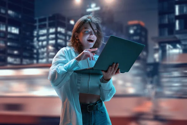 Возбужденная Счастливая Молодая Девушка Смотрит Ноутбук Позитивным Лицом Стоя Ночью — стоковое фото