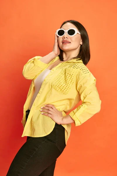 穿着黄色衣服 戴着时髦太阳镜的年轻漂亮姑娘在橙色工作室背景下的画像 情感的概念 生活方式 五彩斑斓的形象 — 图库照片