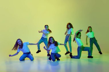 Yetenekli, aktif, küçük kızlar, günlük kıyafetler içinde çocuklar, neon ışıkta yeşil stüdyoda hip-hop dansı yapıyorlar. Çocukluk kavramı, hobi, spor yaşam tarzı