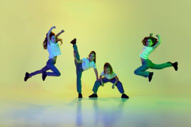 Dört küçük kız, dans eden çocuklar, neon ışıkta yeşil stüdyoya karşı hip-hop stili öğreniyorlar. Sıradan moda. Çocukluk kavramı, hobi, spor yaşam tarzı, aksiyon ve hareket