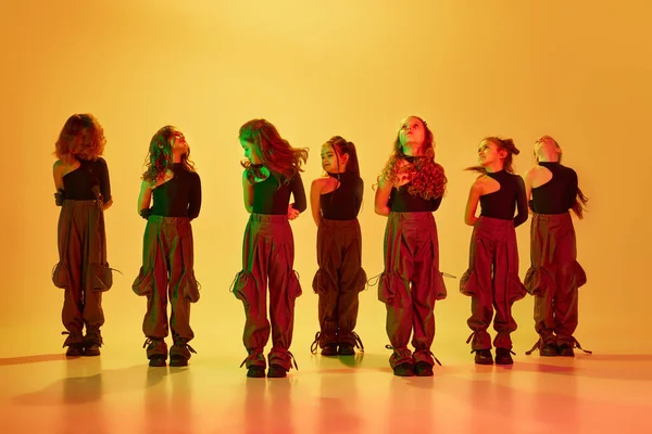 一群小女孩 孩子们 嘻哈舞蹈家穿着运动型服装跳舞 在霓虹灯下在黄色工作室的背景下表演 业余爱好 体育生活方式的概念 — 图库照片