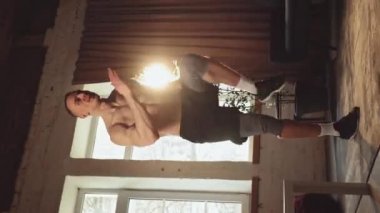 Dikey yerleşim. Kardiyo egzersizleri. Rahatlamış, güçlü, kaslı, gündüz vakti evde üstsüz, koşan genç bir adam. Spor yaşam tarzı kavramı, vücut ve sağlık hizmetleri, fitness