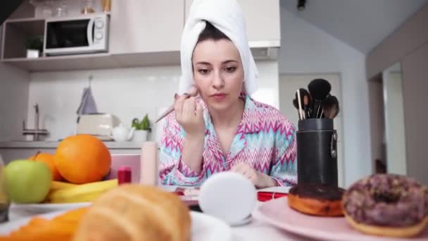 头戴毛巾的年轻漂亮的女人坐在厨房里 准备出门 好好化妆吧 在匆忙中 生活方式的概念 美容程序 美容术 — 图库视频影像