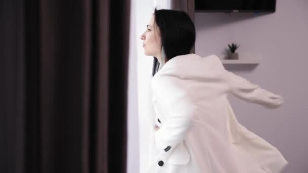 スタイリッシュなビジネス女性は仕事に出かける準備ができて 白いジャケットを着て 窓の近くに立って天気を探しています 朝のホーム準備 ファッション ライフスタイルの概念 — ストック動画
