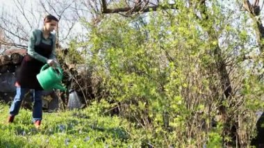 Üniformalı mutlu bir kadın, kendi bahçesinde duruyor ve dans ediyor. Mutlu bahar aktiviteleri, bahçıvanlık, çiftlik zamanı. Komik, çılgın, dans. Doğal ürünler, bahçıvanlık, tarım kavramı