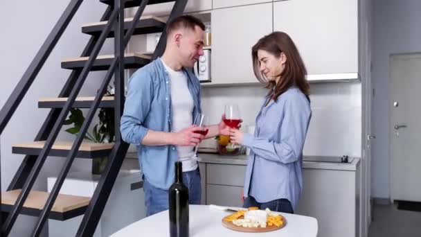 お祝いだ 美しく 愛情のあるカップルがキッチンに立って 赤ワインを飲んでキスをします 朝ごはん ライフスタイル サポートとケアの概念 — ストック動画