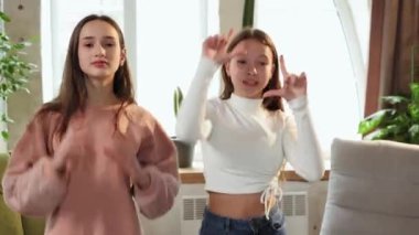 Modern trendler. İki genç kız cep telefonuyla video kaydediyor, dans ediyor, sosyal medya yayını için içerik oluşturuyorlar. Kitle iletişim araçları, blog yazma, modern teknolojiler, nüfuz