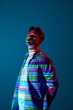 Yenilikçi vizyon. Mavi arka planda çok renkli çizgileri olan dijital neon filtre yansıması olan gündelik giysiler içinde yakışıklı bir genç. Modern sanat kavramı, siber punk, yaratıcılık