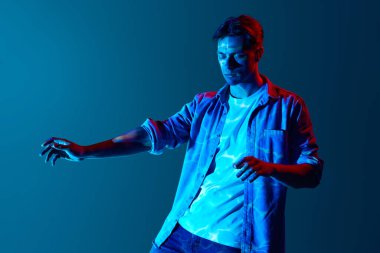 İç his, sezgi. Üstü kapalı giyinmiş genç adam mavi arka planda dijital neon filtre ışığı yansıması ile dikiliyor. Modern fotoğrafçılık, sanat, siber punk, yaratıcılık kavramı