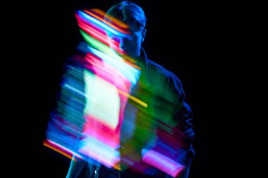 Gerçeküstü, sanal gerçeklik. Karma, çok renkli, dijital neon çizgileri olan genç bir adam koyu arkaplanda yansıyor. Futurizm. Modern fotoğrafçılık, sanat, siber punk, tekno, yaratıcılık kavramı