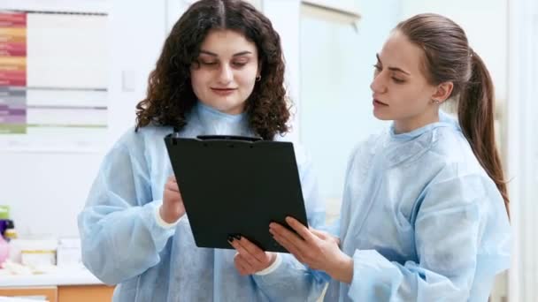 Дві Жінки Лікарі Жилети Захисному Одязі Хірурги Заповнюють Документи Турбота — стокове відео