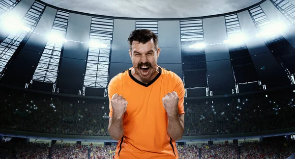 ゲームの前に勝利精神を成長 感情的な男 スポットライトと3Dフィールドに立ってオレンジの制服を着たプロのサッカースポーツマン スポーツ ゲーム 感情の概念 — ストック写真