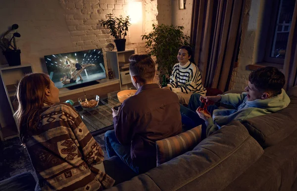 若い人たちは夕方に家で一緒に時間を過ごし ソファで会話し コンソールでオンラインスポーツゲームをプレイしています レジャー活動 楽しみの概念 — ストック写真