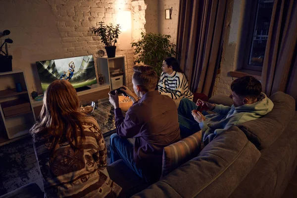 男の子と女の子 友人は自宅で夕方にソファに座って コンソール上でオンラインスポーツゲームをプレイ 楽しい時間だ レジャー活動 楽しみの概念 — ストック写真