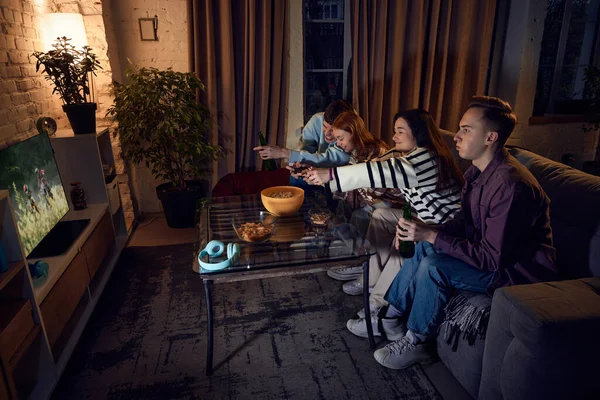 陽気若い人たちは夕方に自宅でソファに座って コンソールでオンラインモータースポーツゲームをプレイします 楽しい時間を一緒に レジャー活動 楽しみの概念 — ストック写真