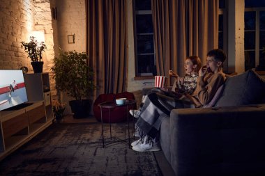 Genç, duygusal bir çift, erkek ve kadın akşamları evde birlikte vakit geçiriyorlar, kanepede oturup televizyon izliyorlar. İlişki kavramı, boş zaman aktivitesi, hafta sonları, eğlence, duygular