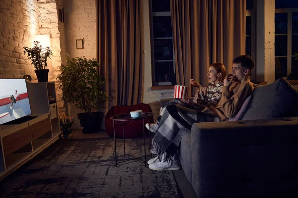 若い感情的なカップル 男性と女性は夜に自宅で一緒に時間を過ごし ソファに座ってテレビ番組を見ています 関係の概念 レジャー活動 楽しみ — ストック写真