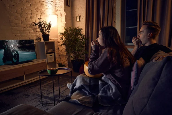 若い美しいカップル 男性と女性は夜に家で一緒に時間を過ごし ソファに座って感情的にテレビを見ています 関係の概念 レジャー活動 楽しみ — ストック写真
