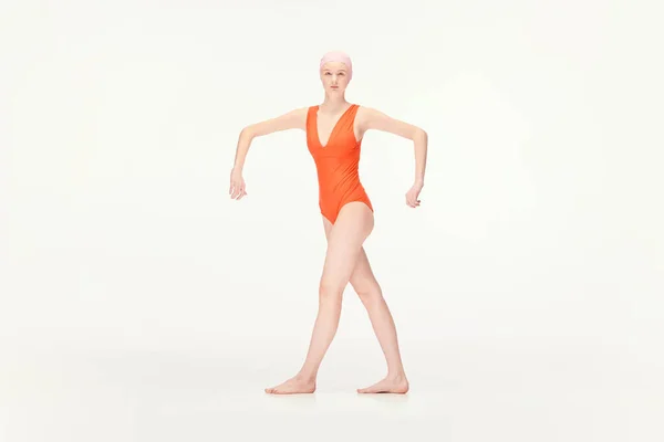 白い背景の上に広い手で隔離された位置に立っている赤い水着と水泳キャップの若い女の子 レトロスタイル スポーツ ファッション ヴィンテージの概念 広告のコピースペース — ストック写真