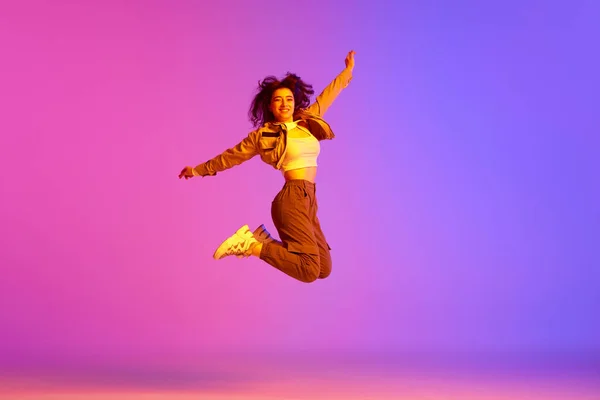 스포츠 스타일의 댄서인 소녀는 라이트의 바탕에 점프하고 다행이네요 움직임의 — 스톡 사진
