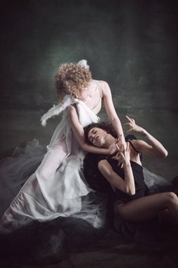 Derin aşk ve kurtuluş. İki kadının portresi, melek ve şeytan koyu yeşil, klasik arka plana karşı. Seçim yapıyorum. Tarih kavramı, yeniden yapım, iyi ve kötü, yaratıcı fotoğrafçılık