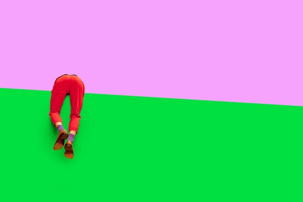 Male legs in red pants and classical shoes over vivid purple and green background. Empty space to insert your text. Concept of art, creative vision, fashion. Complementary colors. Copy space for ad