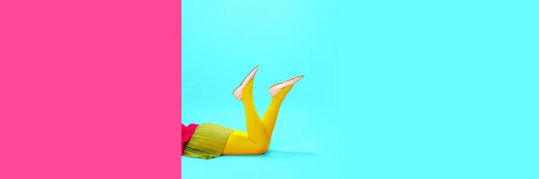 Female legs in yellow tights over vivid pink and blue background. Shopping, season sales. Pop art photography. Concept of art, creative vision, fashion. Complementary colors. Banner. Copy space for ad