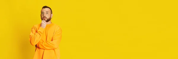 広い目でポーズをとるカジュアルなスウェットシャツに身を包んだ男の肖像画は 鮮やかな黄色の背景に対して頬を表現しています ライフスタイル 表情の概念 バナーだ 広告のコピースペース — ストック写真