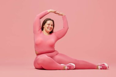 Kişisel bakım ve refah. Pembe stüdyo geçmişine karşı spor giyimi eğitimi alan şişman bir kadın. Motivasyon. Spor anlayışı, vücut pozitifliği, kilo kaybı, vücut ve sağlık hizmetleri