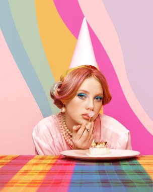Doğumgünü duygusuz bakışı. Çok renkli saçlı güzel bir genç kız, renkli ve soyut arka planda pasta içerken sigara içiyor. Yemek sanatı. Retro tarz kavramı, yaratıcı vizyon, güzellik, moda.
