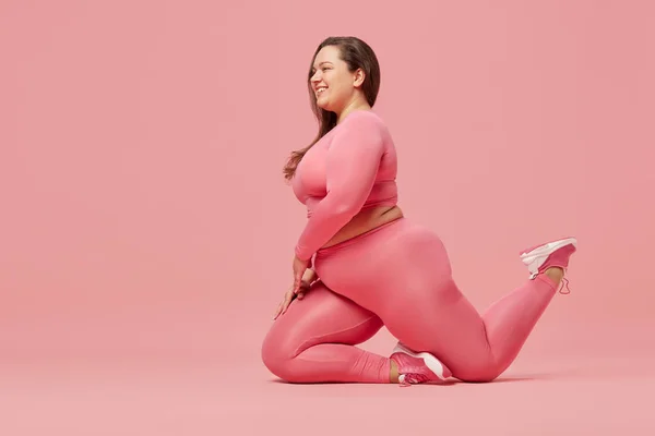 有进取心的女人 在粉色工作室的背景下 在运动服方面有超重的身体训练 体格积极 体重减轻 身体和保健的概念 — 图库照片