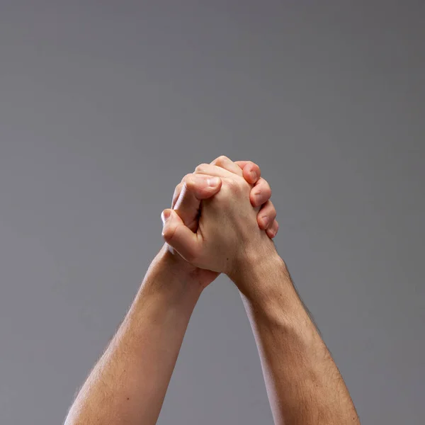 Male hands holding against grey background. Giving support, acceptance and care. Freedom, equality and humanity. Concept of human relation, community, symbolism, culture, communication