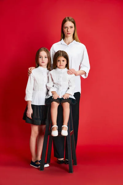 一个美丽的家庭 母亲和两个小女孩在红色的工作室背景下穿着同样风格的衣服 生活方式 爱情的概念 — 图库照片