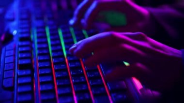 İnsan elinin çok renkli ışıklarla hızlı bir şekilde bilgisayar klavyesine yazışı. Çevrimiçi iletişim, mesajlaşma, kodlama, oyun. İş anlayışı, oyun, modern teknolojiler, serbest çalışma