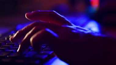 Erkek ellerine yakın çekim, sanal sporcu online oyunlar oynamak için bilgisayar klavyesi kullanıyor. Neon renkli uzay. Siber spor kavramı, çevrimiçi video oyunları, modern teknolojiler, serbest çalışma