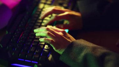 Arka planda çalışan, kodlayan, iletişim kuran, arka planda çalışan erkek ellerinin yakın çekimi. Neon renkli arka plan. İş anlayışı, oyun, modern teknolojiler, serbest çalışma