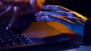 Dokunmatik ped kullanan, dizüstü bilgisayarda daktilo kullanan, ev ofisinde neon ışıklarla çalışan kadınların yakın plan görüntüsü. İş, uzaktan çalışma, programlama, modern teknolojiler, serbest çalışma kavramı