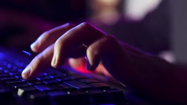 オンラインゲームをプレイするためにコンピュータキーボードを使用して男性の手のクローズアップ ネオンカラーの画像 サイバースポーツマン サイバースポーツの概念 オンラインビデオゲーム 現代技術 フリーランス — ストック動画