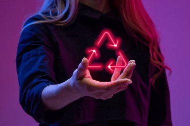 Kadın elinde sanal, dijital, neon renkli geri dönüşüm sembolü tutuyor. Küresel iş dünyasındaki modern teknolojiler. İş kavramı, modern teknolojiler, ağ, dijitalleştirme
